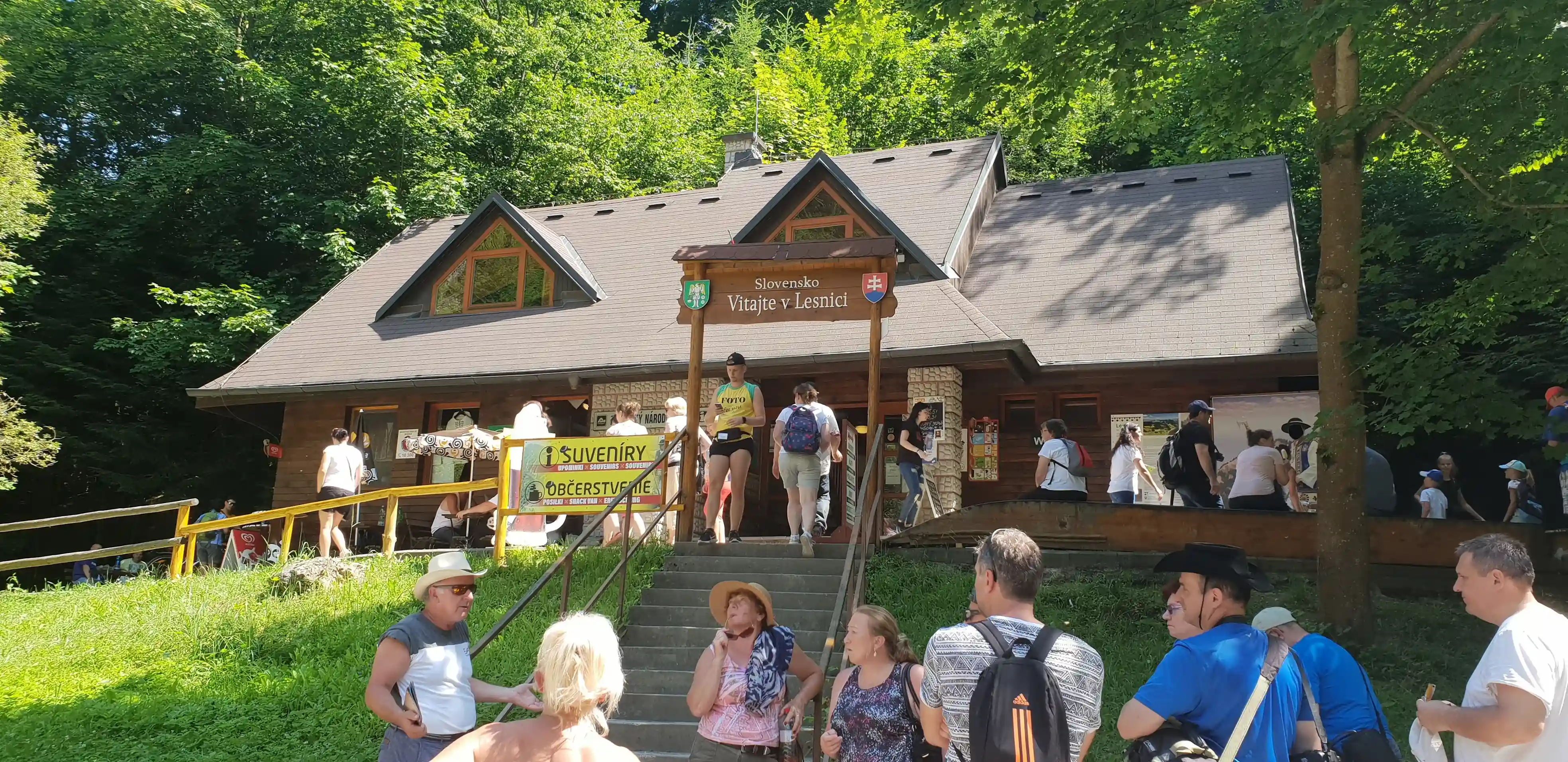 A group of people gathered outside a building surrounded by trees and grass.