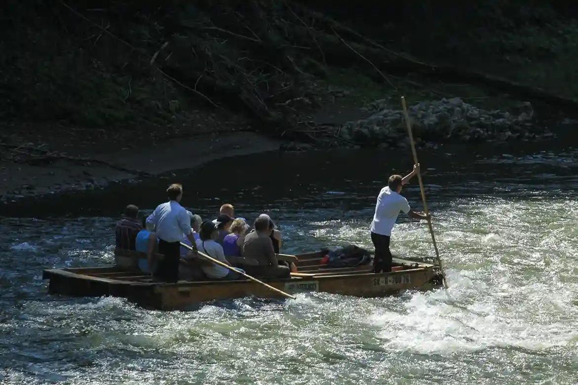 A group of people paddling together in an inflatable boat on a lake, surrounded by nature.